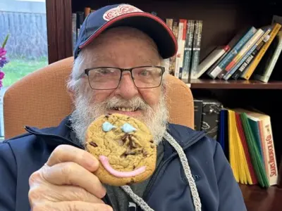 Senior attending adult day program smiling holding a cookie