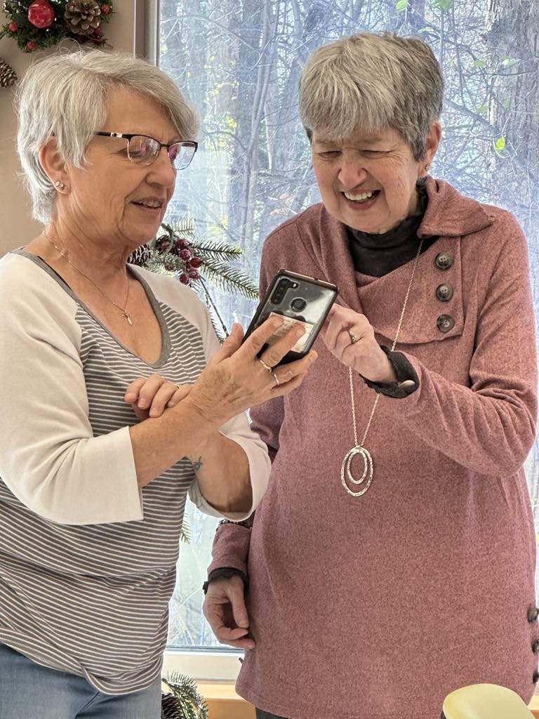 Two seniors attending Adult Day program looking at a smartphone