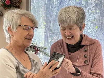 Two seniors attending Adult Day program looking at a smartphone