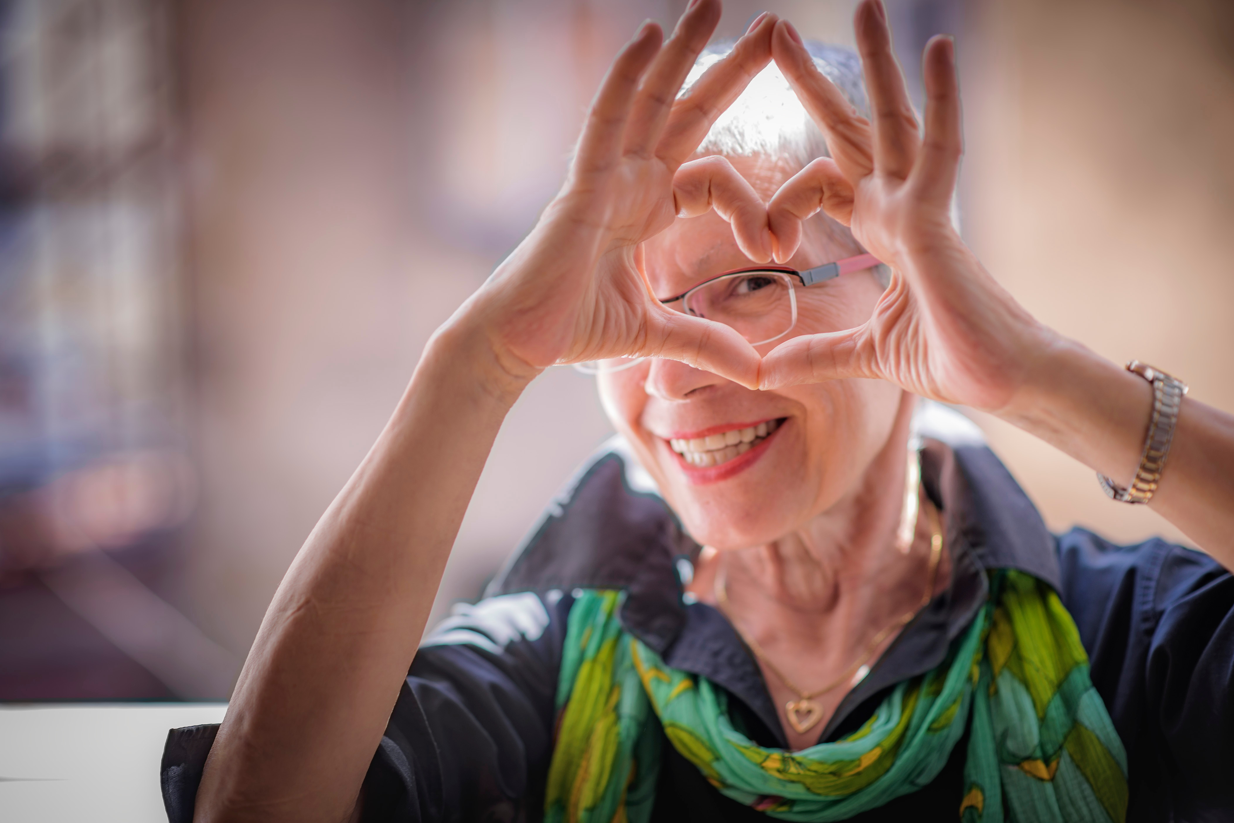 woman smiling looking through hand hearts